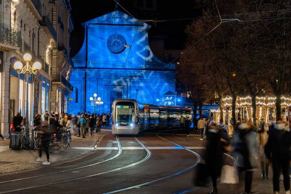 Photographie d'un tramway du réseau TAG circulant au milieu de passants faisant leurs courses pour les fêtes de fin d'année. 