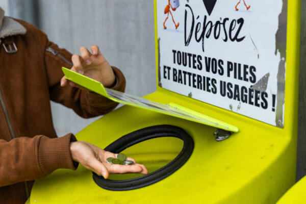 Une personne jette des piles au lithium dans un conteneur prévu à cet effet