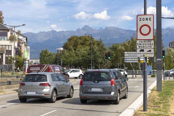 Des voitures circulent dans une zone à faibles émissions marquée par un panneau de signalisation routière. 