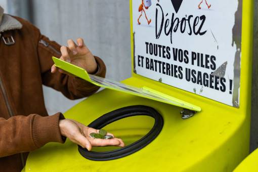 Une personne jette des piles au lithium dans un conteneur prévu à cet effet